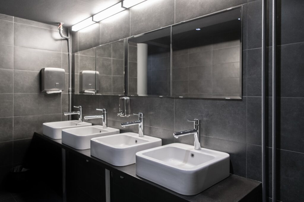 Faucets with washbasin in public restroom in grey colors