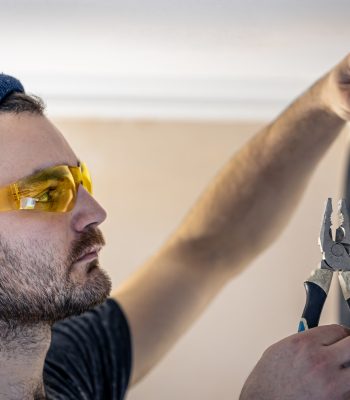 An electrician is mounting electric sockets on the white wall indoors.