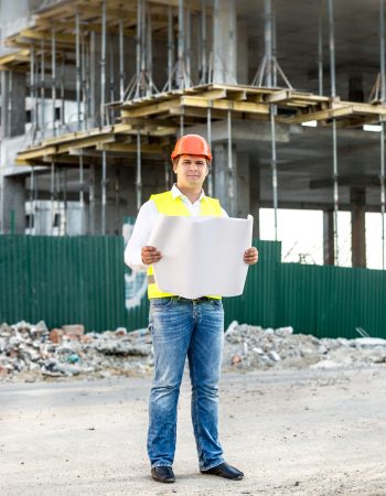 architect at work reading blueprints on building site